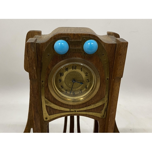 59 - AN ARTS AND CRAFTS WOODEN CLOCK WITH INSET INKWELLS