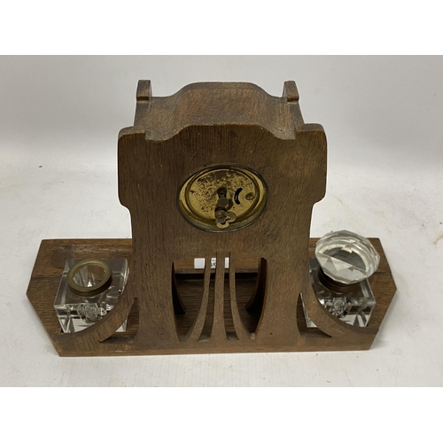 59 - AN ARTS AND CRAFTS WOODEN CLOCK WITH INSET INKWELLS