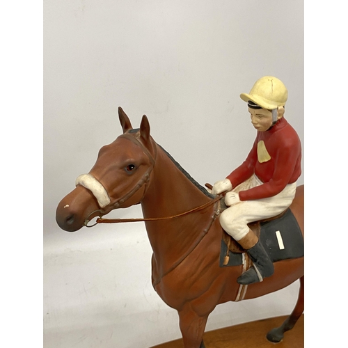 65 - A BESWICK RED RUM HORSE AND JOCKEY FIGURE ON WOODEN PLINTH BASE, HEIGHT 35CM