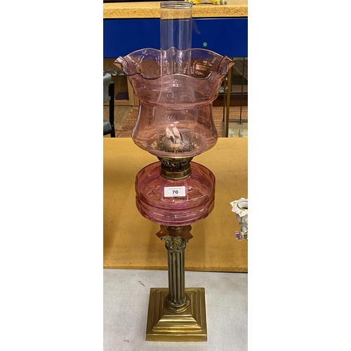 70 - A VINTAGE BRASS CORNINTHIAN COLUMN OIL LAMP WITH CRANBERRY GLASS RESERVOIR, HEIGHT 72CM