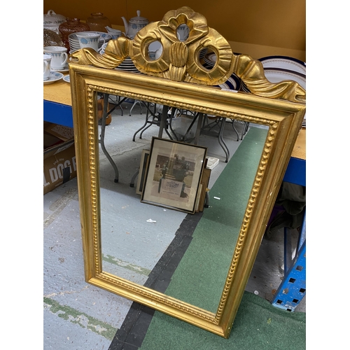 107 - AN ORNATE GILT FRAMED MIRROR WITH RIBBON DESIGN TOP