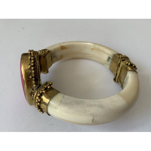 600 - AN ORNATE BANGLE WITH A PINK OVAL STONE