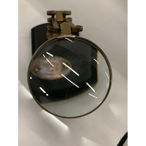 192 - A BRASS MAGNIFYING GLASS ON A WOODEN BASE