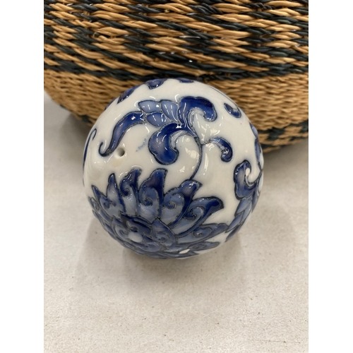 915 - A QUANTITY OF CERAMIC BLUE AND WHITE ORNAMENTAL BALLS IN A VINTAGE BASKET