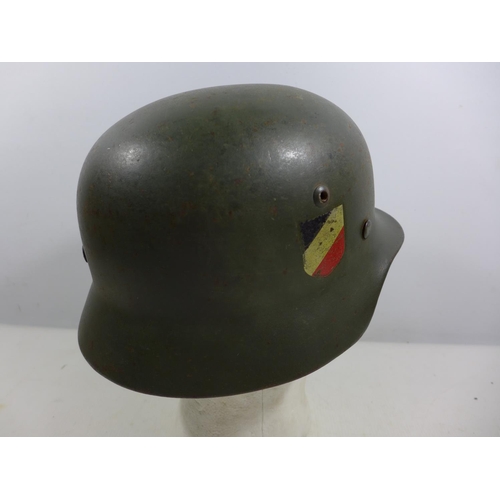 307 - A GERMAN GREEN PAINTED METAL HELMET WITH EAGLE AND SWASTIKA DECORATION AND LEATHER LINING