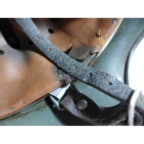 307 - A GERMAN GREEN PAINTED METAL HELMET WITH EAGLE AND SWASTIKA DECORATION AND LEATHER LINING