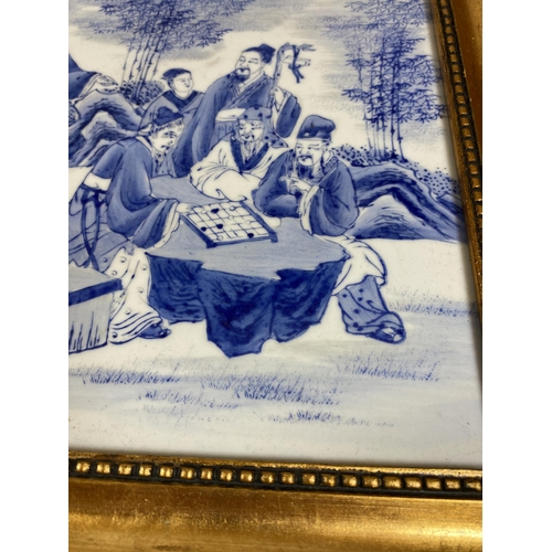 386 - A GILT FRAMED CHINESE BLUE AND WHITE PORCELAIN PLAQUE WITH SCHOLAR FIGURES DESIGN, SIGNED TO TOP LEF... 