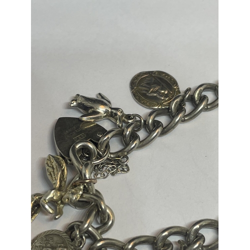 530 - A SILVER CHARM BRACELET WITH TEN CHARMS AND A HEART PADLOCK