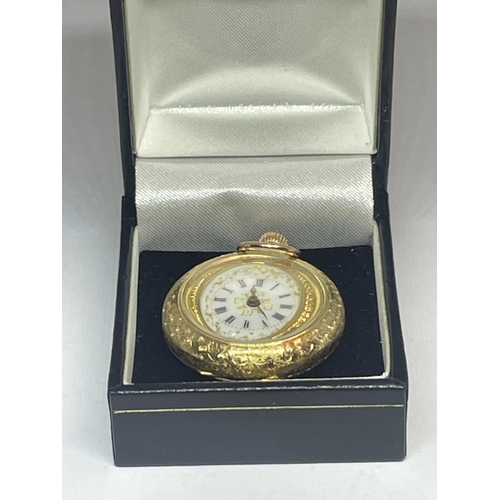 553 - AN ORNATE 18 CARAT GOLD FOB WATCH WITH WHITE ENAMAL FACE AND ROMAN NUMERALS WITH FLOWER DESIGN TO TH... 