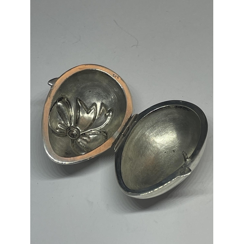 577 - A SILVER EGG SHAPED PILL BOX WITH RIBBON DESIGN ON THE LID