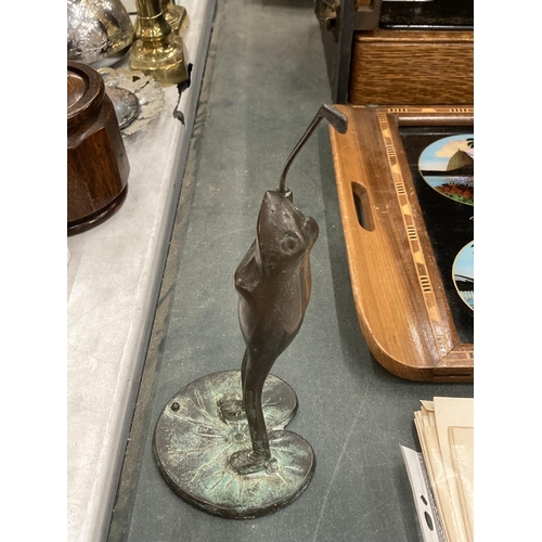 299 - A BRONZE STYLE FROG PLAYING GOLF ON A LILY PAD, HEIGHT 25CM