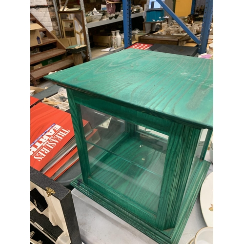 448 - A GREEN WOODEN DISPLAY CABINET WITH A GLASS SHELF