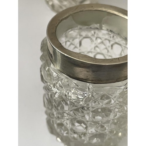 86 - THREE CUT GLASS ITEMS TO INCLUDE A JAR WITH A HALLMARKED BIRMINGHAM COLLAR, A BOTTTLE WITH A HALLMAR... 