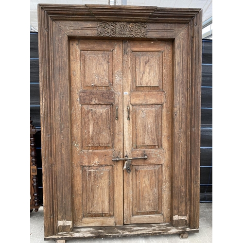 2848 - A PAIR OF INDIAN HARDWOOD PANELLED DOORS WITH BRASS FITTINGS + CARVED CORNICE, 84 X 58