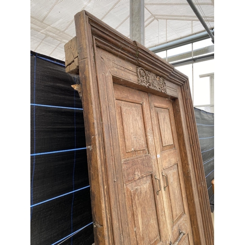 2848 - A PAIR OF INDIAN HARDWOOD PANELLED DOORS WITH BRASS FITTINGS + CARVED CORNICE, 84 X 58