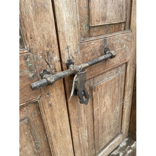 2848 - A PAIR OF INDIAN HARDWOOD PANELLED DOORS WITH BRASS FITTINGS + CARVED CORNICE, 84 X 58