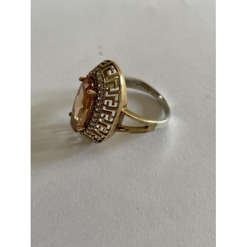 551 - A DECORATIVE SILVER AND GOLD RING WITH LARGE AMBER COLOURED STONE SURROUNDED BY CLEAR STONES SIZE T/... 