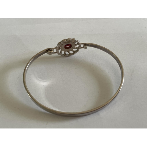 557 - A SILVER BANGLE WITH RED STONE