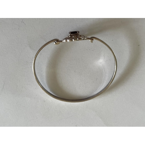 557 - A SILVER BANGLE WITH RED STONE