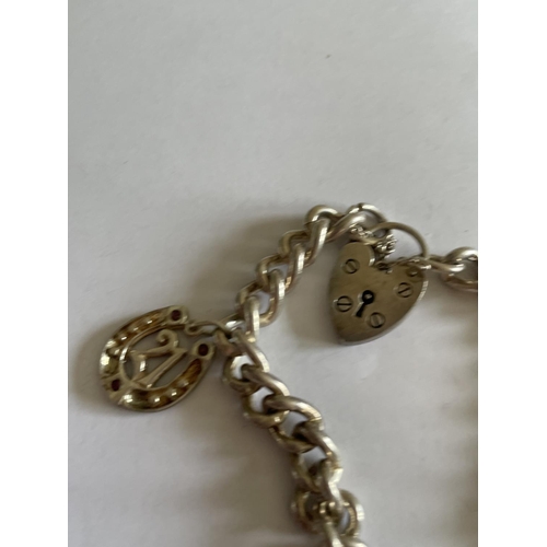 602 - A HEAVY SILVER BRACELET WITH TWO CHARMS AND A HEART SHAPED PADLOCK