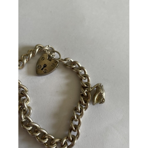 602 - A HEAVY SILVER BRACELET WITH TWO CHARMS AND A HEART SHAPED PADLOCK