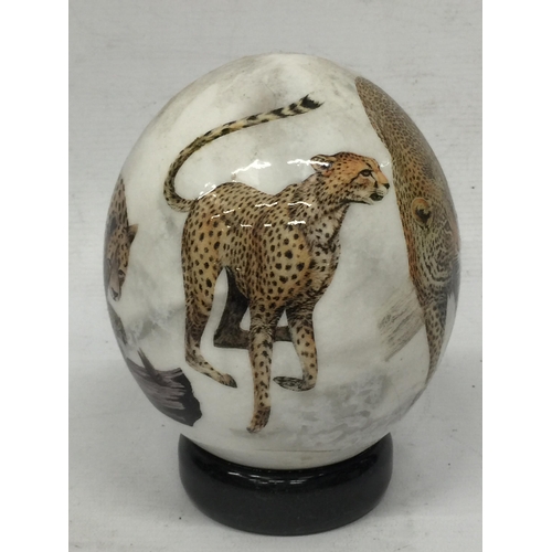 12 - A HAND PAINTED OSTRICH EGG ON STAND WITH CHEETAH DESIGN, INDISTINCTLY SIGNED
