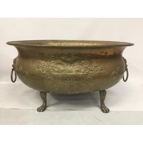 43 - A LARGE BRASS BOWL ON PAW FEET WITH FIGURAL HANDLES