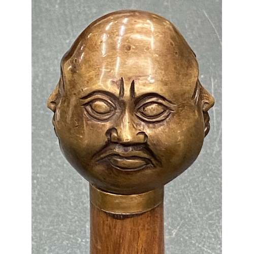 129 - A WALKING STICK WITH A BRASS FOUR FACED BUDDAH HANDLE