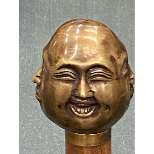 129 - A WALKING STICK WITH A BRASS FOUR FACED BUDDAH HANDLE