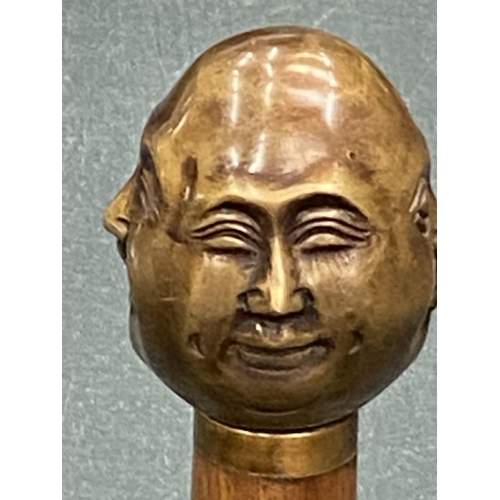 129 - A WALKING STICK WITH A BRASS FOUR FACED BUDDAH HANDLE