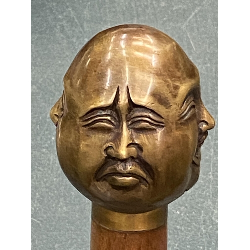 129 - A WALKING STICK WITH A BRASS FOUR FACED BUDDAH HANDLE