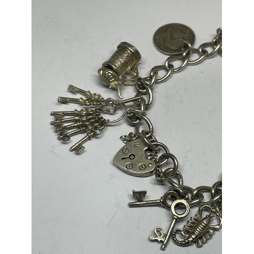 587 - A SILVER CHARM BRACELET WITH ELEVEN CHARMS AND A HEART PADLOCK