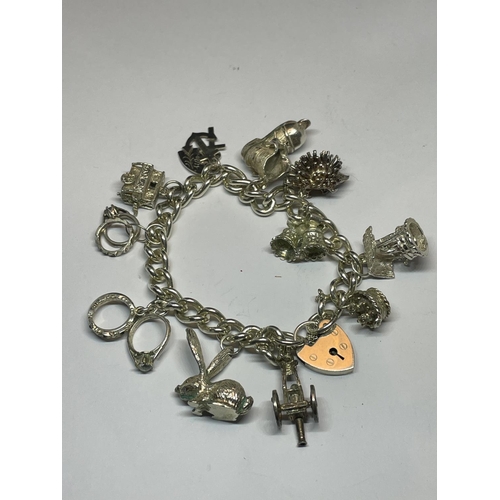 604 - A SILVER CHARM BRACELET WITH ELEVEN CHARMS AND A HEART PADLOCK