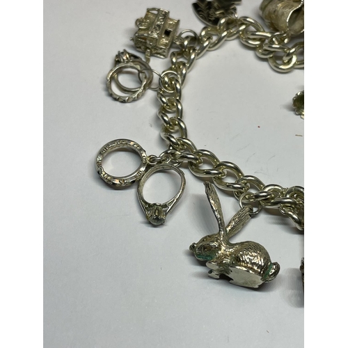 604 - A SILVER CHARM BRACELET WITH ELEVEN CHARMS AND A HEART PADLOCK