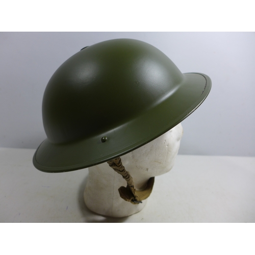 332 - A MID 20TH CENTURY GREEN PAINTED METAL BRITISH HELMET AND LINER