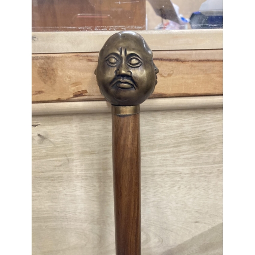 860 - A WALKING STICK WITH A BRASS FOUR FACED BUDDAH HANDLE