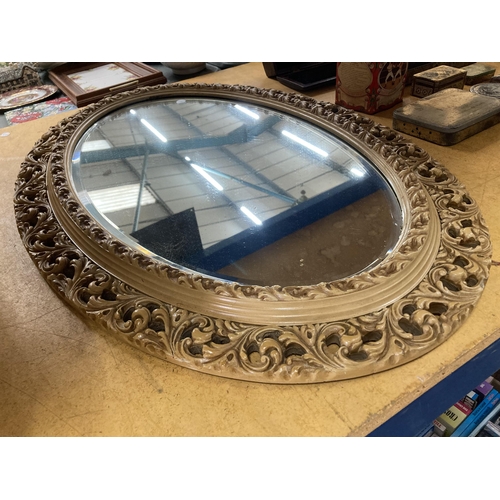 878 - AN OVAL RESIN FRAMED MIRROR 84CM X 58CM