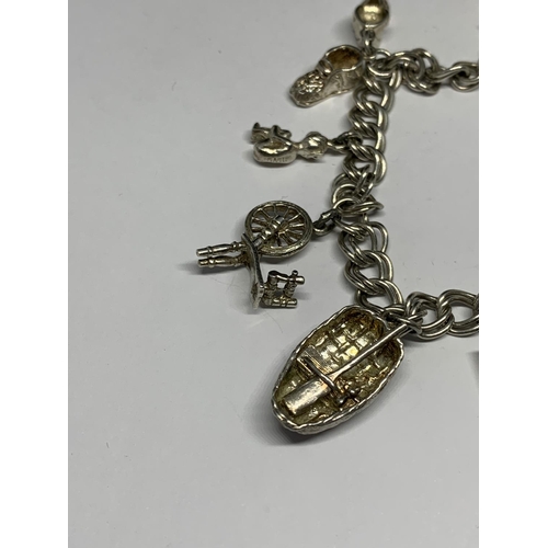 691 - A SILVER CHARM BRACELET WITH SEVEN CHARMS AND A HEART PADLOCK