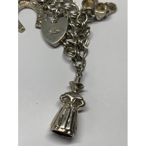 691 - A SILVER CHARM BRACELET WITH SEVEN CHARMS AND A HEART PADLOCK