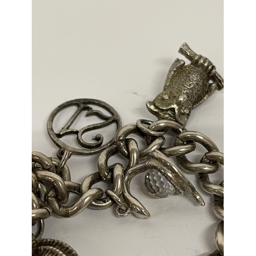 699 - A SILVER CHARM BRACELET WITH THIRTEEN VARIOUS CHARMS