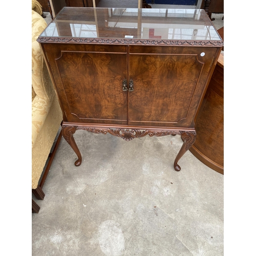 2583 - A WALNUT TWO DOOR COCKTAIL CABINET WITH CARVED RAIL, ON CABRIOLE LEGS, 35