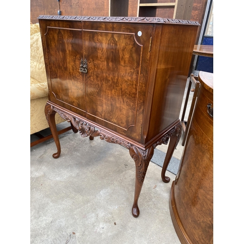 2583 - A WALNUT TWO DOOR COCKTAIL CABINET WITH CARVED RAIL, ON CABRIOLE LEGS, 35