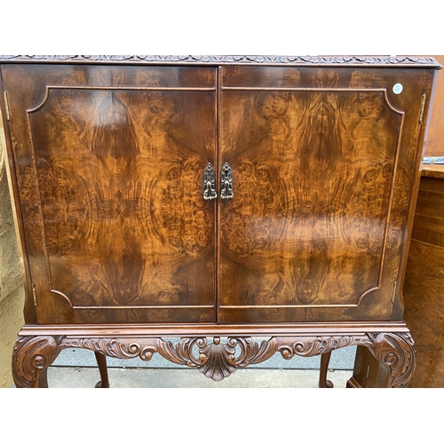 2583 - A WALNUT TWO DOOR COCKTAIL CABINET WITH CARVED RAIL, ON CABRIOLE LEGS, 35