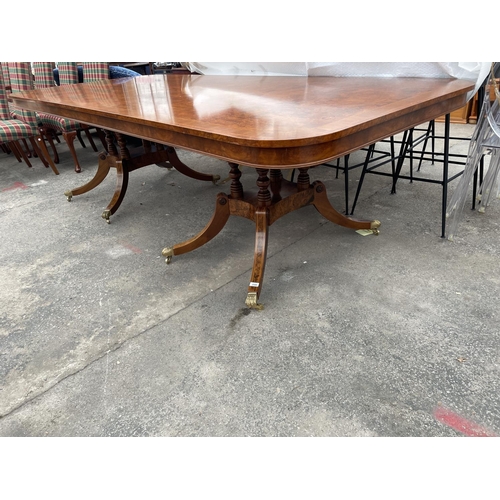 2580 - A REGENCY STYLE TWIN PEDESTAL WALNUT AND MAHOGANY CROSSBANDED DINING TABLE, THE PEDESTALS HAVING FOU... 