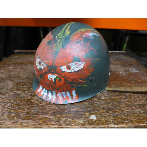 399 - AN UNUSUAL LATE 20TH CENTURY U.S ARMY HELMET LINER WITH HAND PAINTED DECORATION OF A DEVIL FACE WITH... 