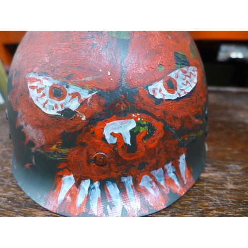 399 - AN UNUSUAL LATE 20TH CENTURY U.S ARMY HELMET LINER WITH HAND PAINTED DECORATION OF A DEVIL FACE WITH... 