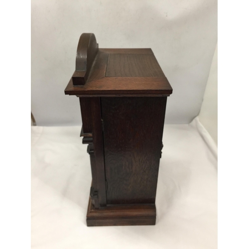 5 - A VINTAGE CARVED OAK MANTLE CLOCK WITH PENDULUM AND KEY