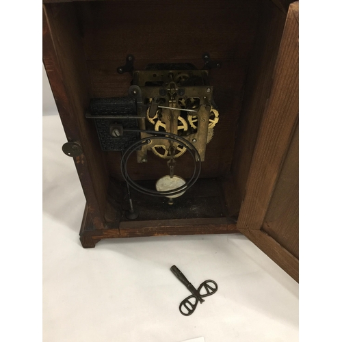 5 - A VINTAGE CARVED OAK MANTLE CLOCK WITH PENDULUM AND KEY