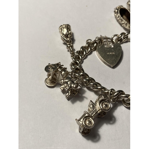 646 - A SILVER CHARM BRACELET WITH TEN CHARMS AND A HEART PADLOCK