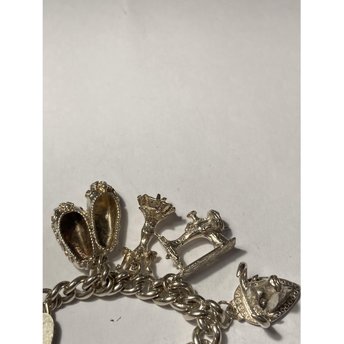 646 - A SILVER CHARM BRACELET WITH TEN CHARMS AND A HEART PADLOCK